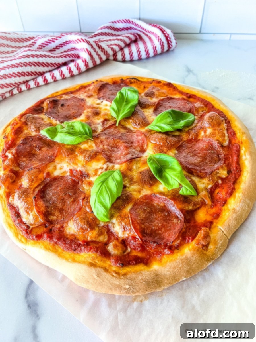 Foolproof Bisquick Pizza Dough 2 Homemade cheese and pepperoni pizza garnished with fresh basil leaves, showcasing a perfectly golden Bisquick crust.
