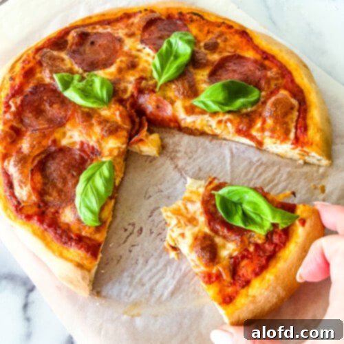 Foolproof Bisquick Pizza Dough 11 Woman's hand removing slice of homemade pepperoni pizza.