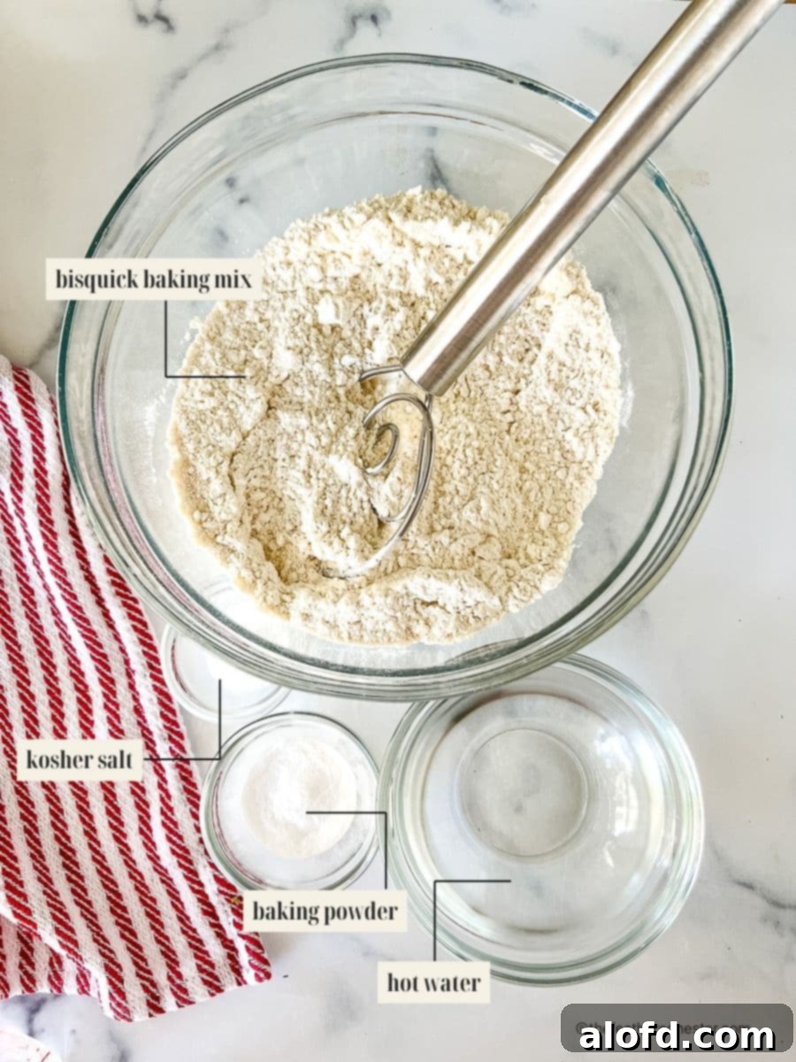 Foolproof Bisquick Pizza Dough 3 A selection of ingredients for Bisquick pizza dough, including Bisquick mix, flour, baking powder, Italian seasoning, olive oil, and hot water, neatly arranged on a counter.