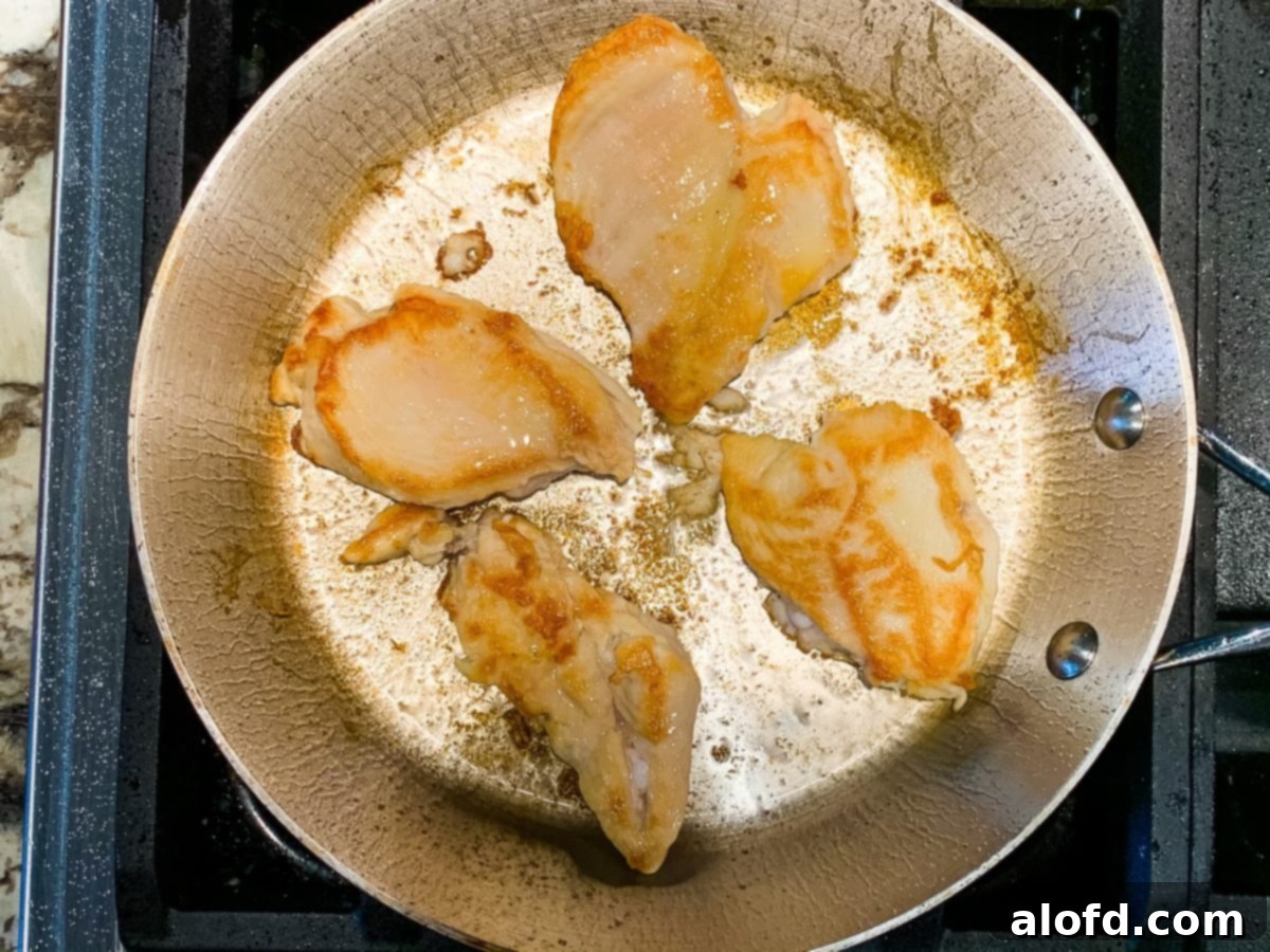 Pan searing poultry cutlets in a large skillet, showing a golden crust.