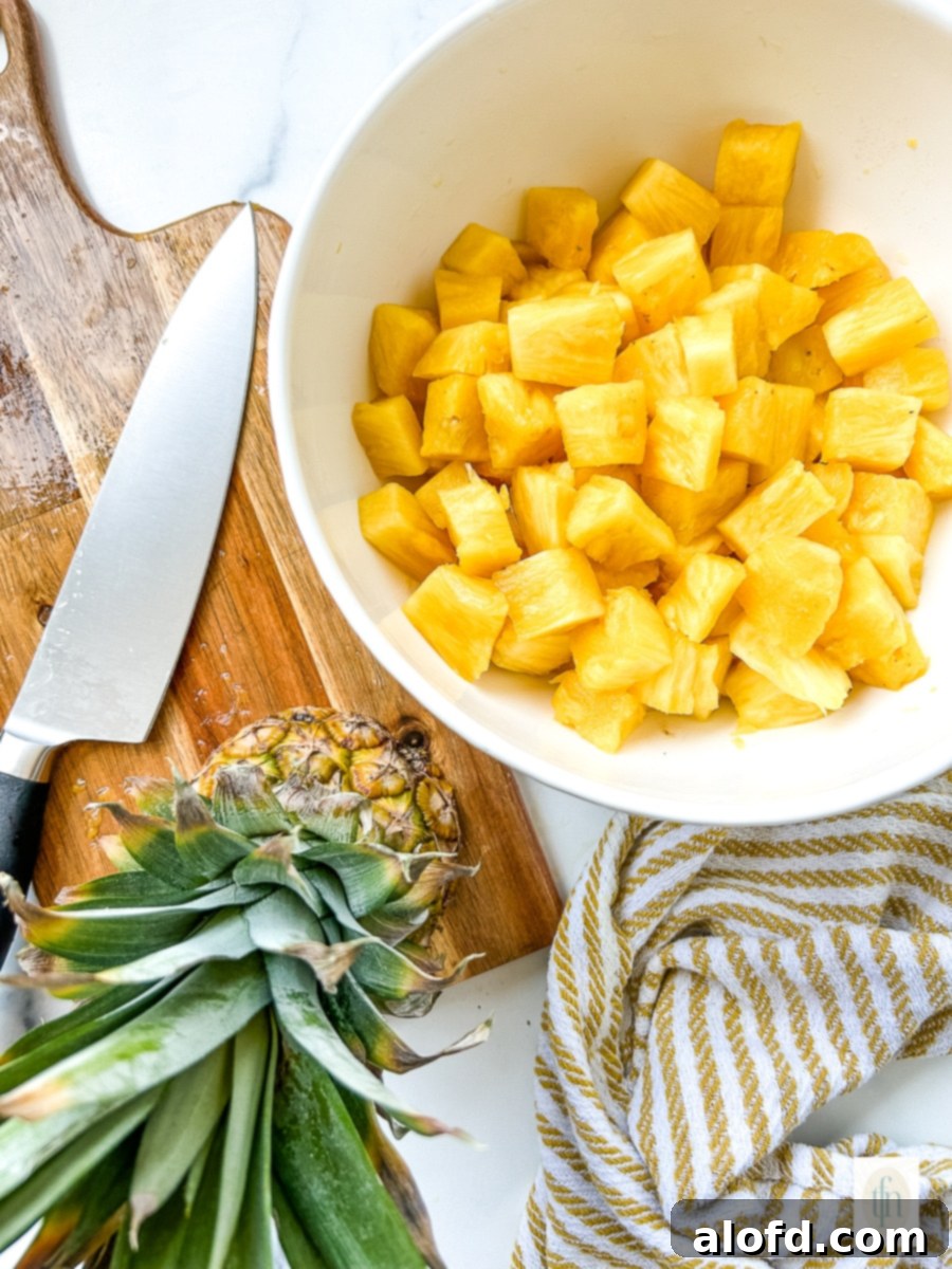 A white bowl brimming with fresh pineapple chunks, perfectly cut and ready for consumption or storage.