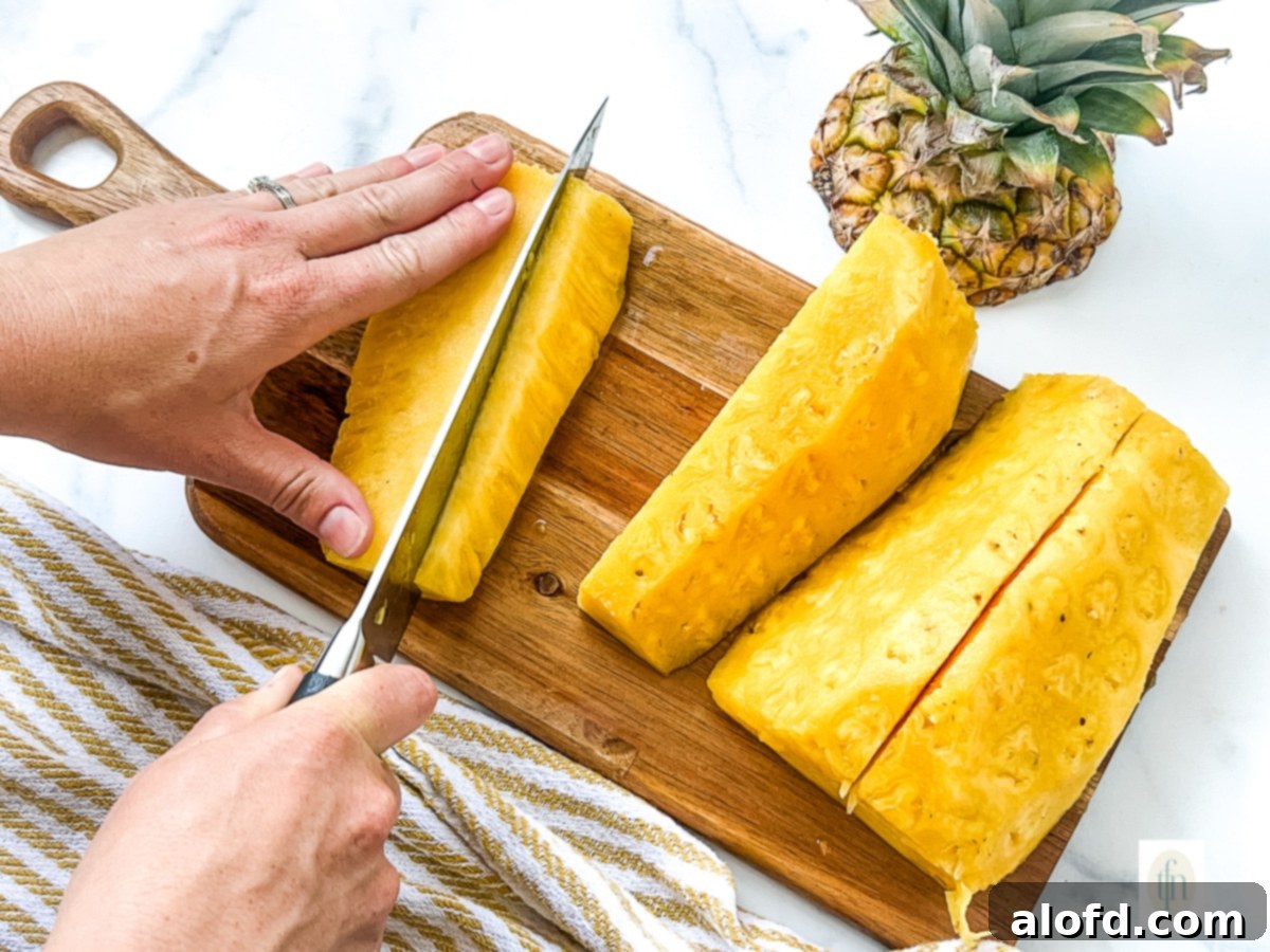 Demonstration of using a large kitchen knife to remove the pineapple core after the fruit has been peeled and sectioned.