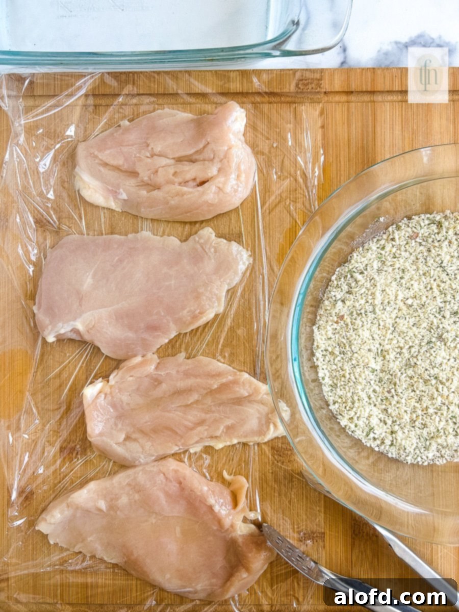Golden Panko-Crusted Chicken Breast 4 Several pieces of uncooked boneless skinless chicken breast flattened on plastic wrap, next to a bowl of seasoned panko bread crumbs.
