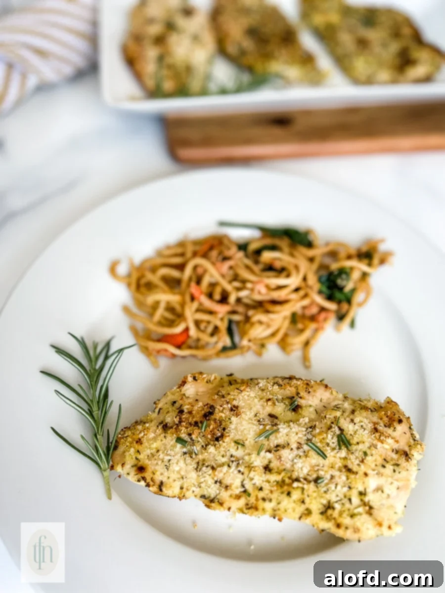 Golden Panko-Crusted Chicken Breast 7 Baked lemon pepper panko crusted chicken breast on a plate with cooked pasta and fresh parsley.