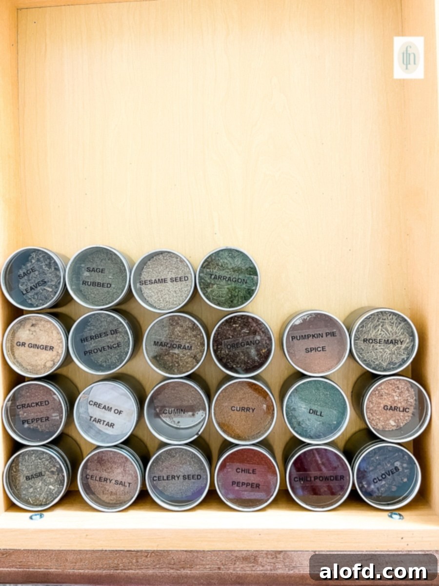 Decluttered and organized spice drawer filled with labeled canisters of dried spices and seasonings.