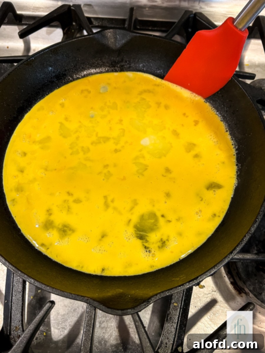 Tangy Sourdough Morning Stack 6 Image shows how to make fluffy scrambled eggs in a skillet, with edges beginning to set.