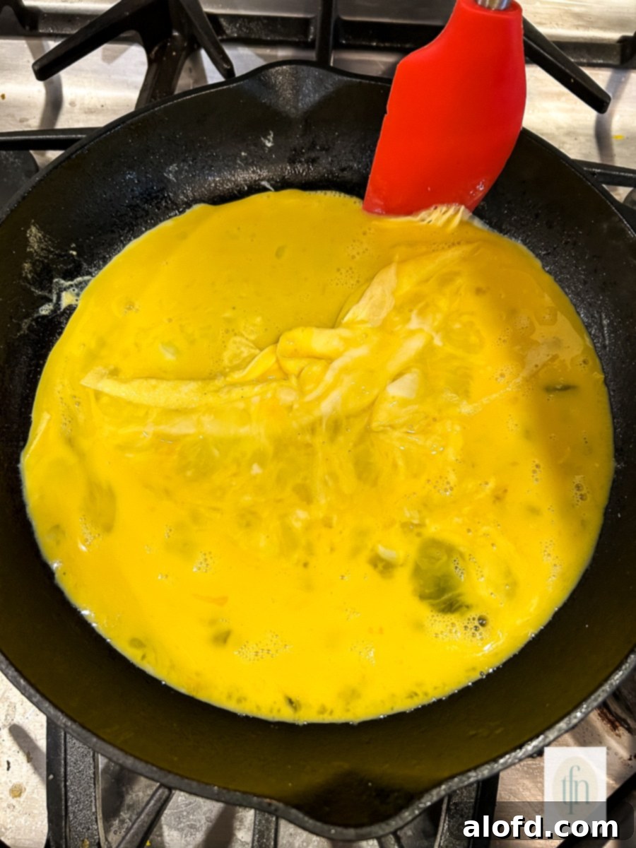 Tangy Sourdough Morning Stack 7 Scrambling fluffy eggs in a small skillet with a silicone spatula.