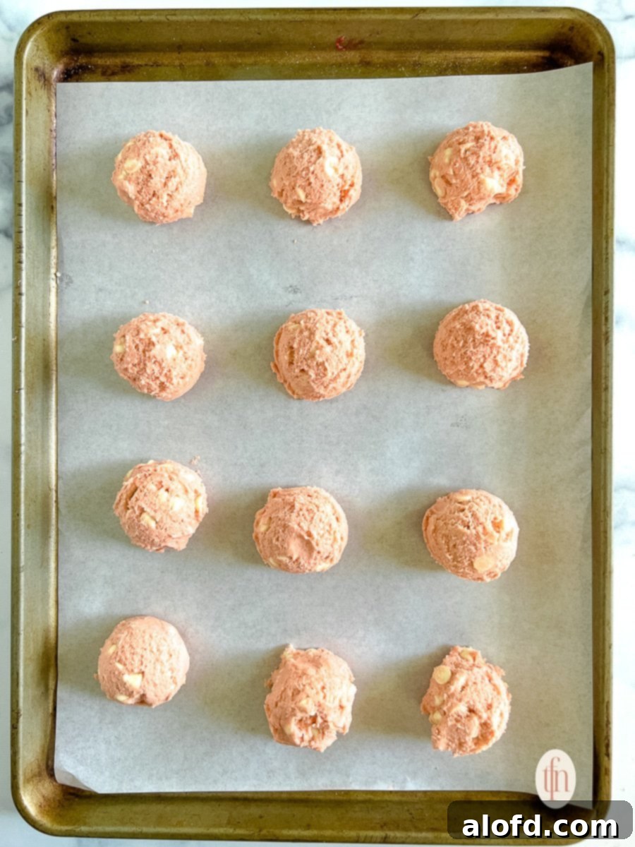 Strawberry Cheesecake Cookie Bliss 8 Unbaked cheesecake cookies on a parchment lined baking sheet, perfectly portioned.