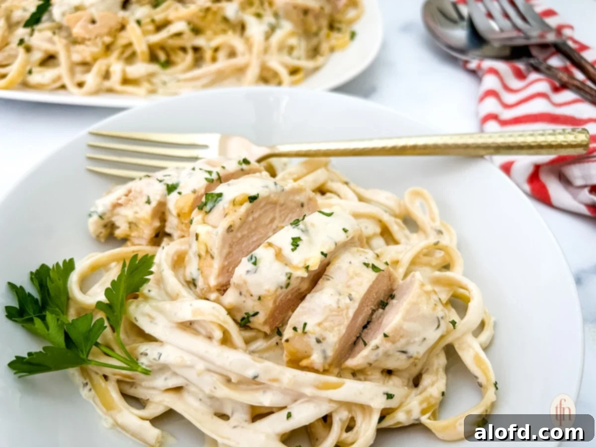 Garlic parmesan chicken pasta on a white bowl with fork.