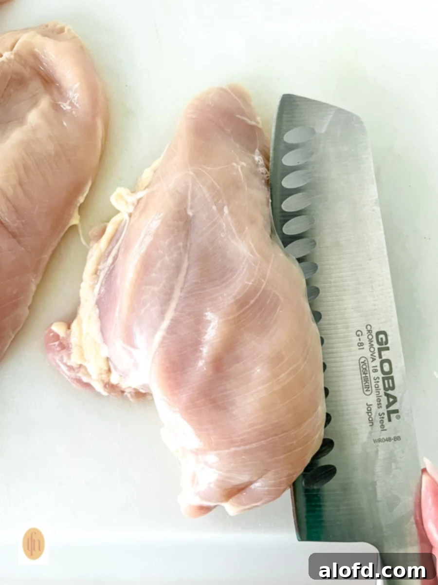 A chef's knife cutting boneless breast into two cutlets.