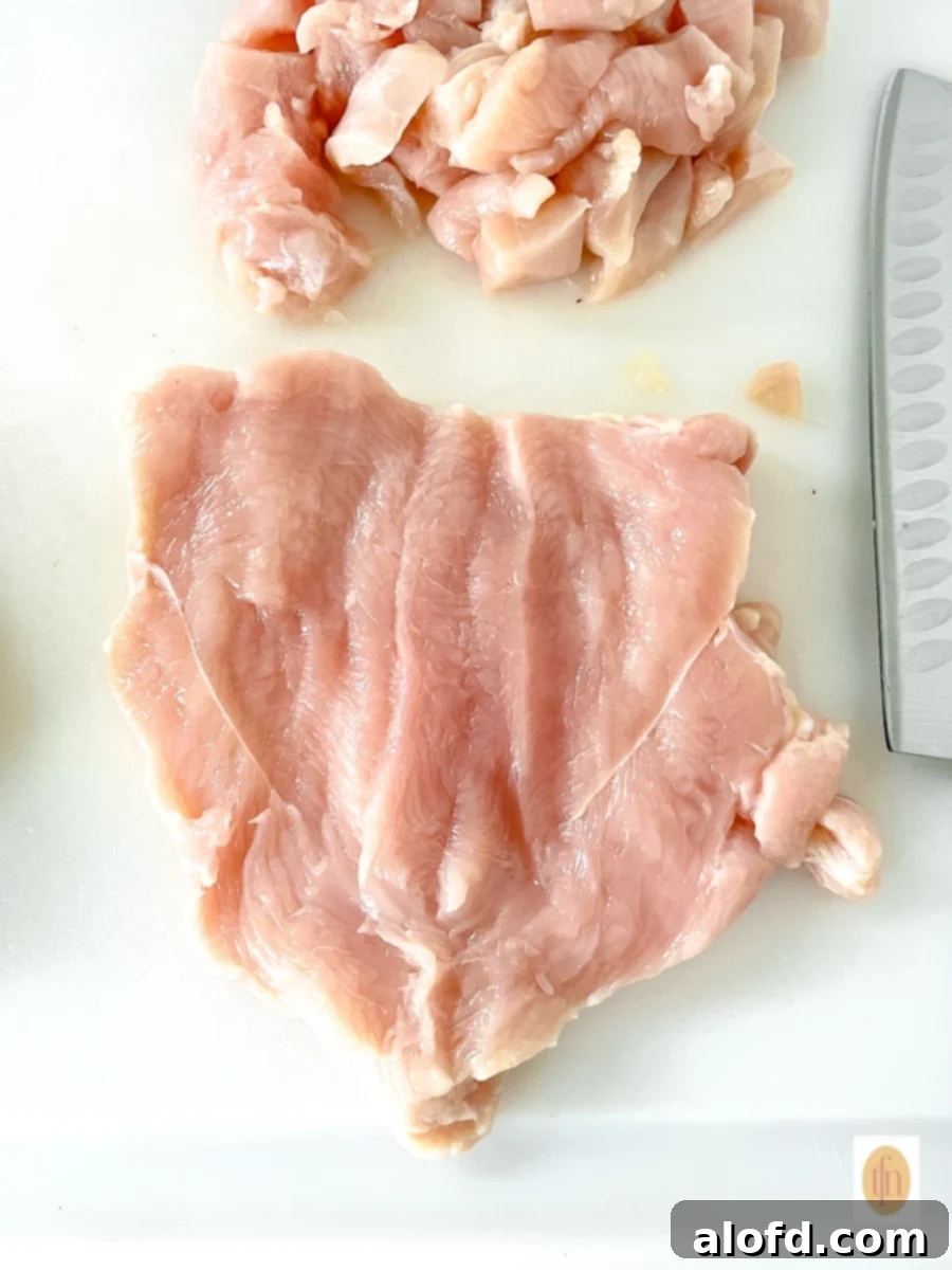 Butterflied piece of raw poultry on a white cutting board.