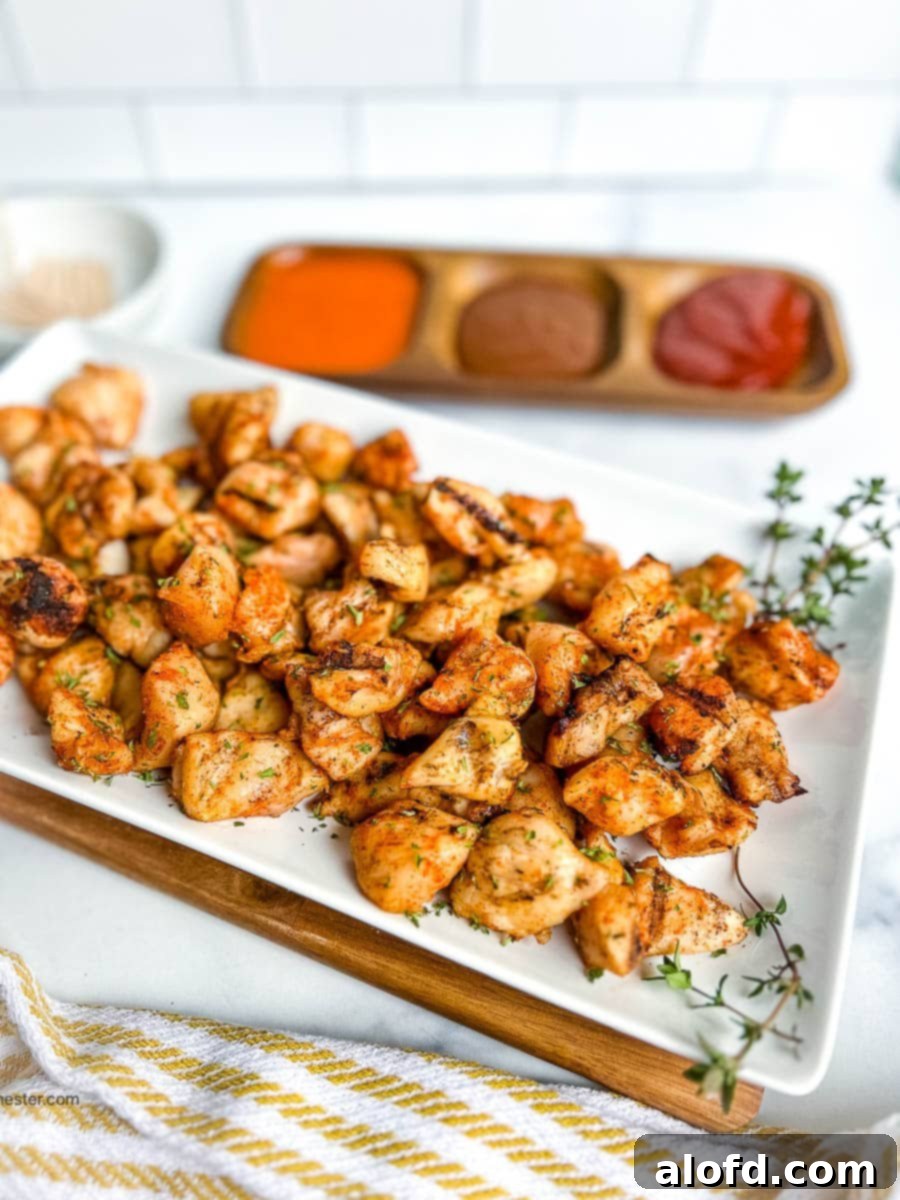 Grilled chicken nuggets on a serving platter next to dipping sauces.
