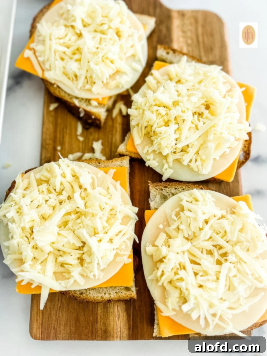 Tangy Sourdough Golden Cheese Melt 4 Hands assembling sourdough grilled cheese sandwiches with slices of cheddar, havarti, and provolone cheese.