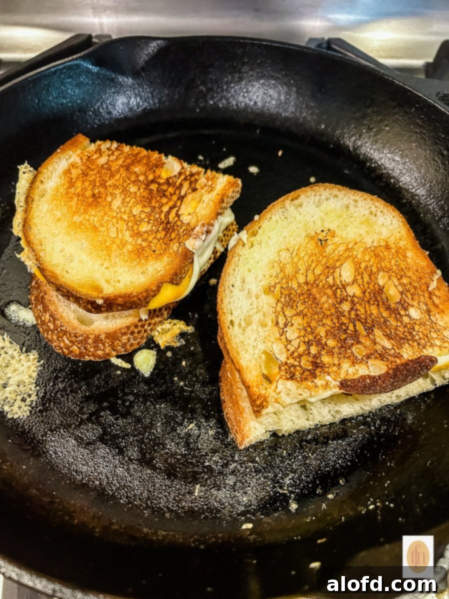 Tangy Sourdough Golden Cheese Melt 6 Cooking sourdough grilled cheese sandwiches in a cast iron skillet over low heat.