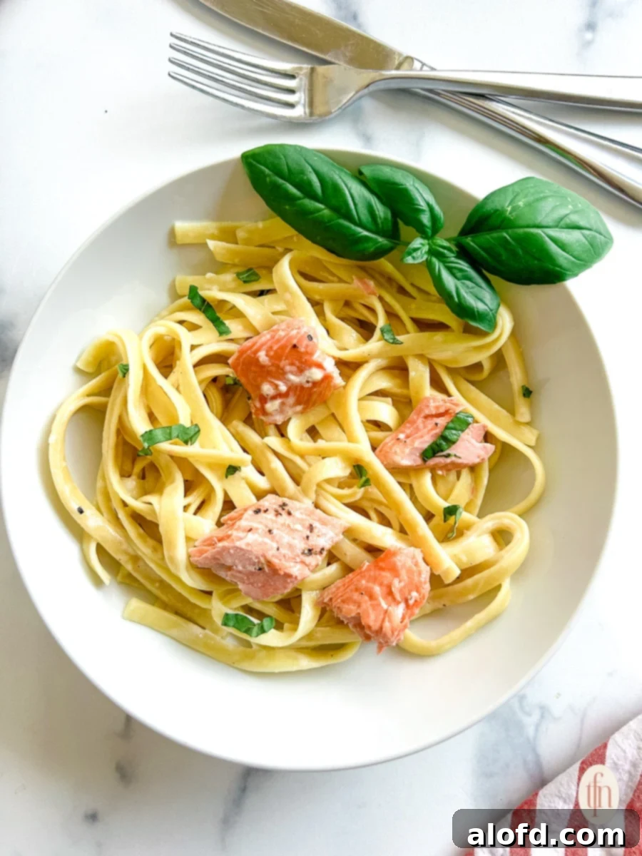 Decadent Salmon Alfredo 2 30 minute dinner of salmon alfredo fettuccine, featuring a vibrant orange salmon fillet atop a bed of creamy pasta.