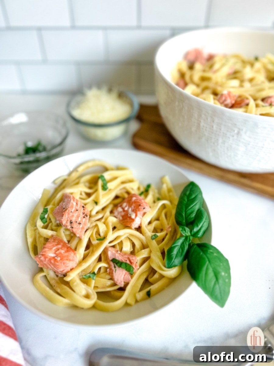 Decadent Salmon Alfredo 10 A large dish of baked salmon alfredo pasta, garnished with fresh herbs, ready to be served for a delightful dinner.