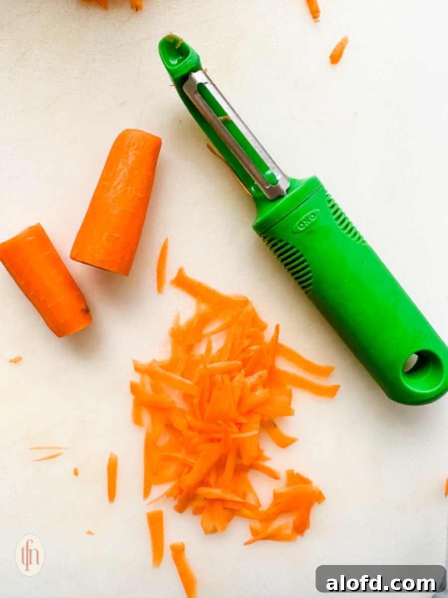 small pieces of raw orange vegetable next to a green colored vegetable peeler.