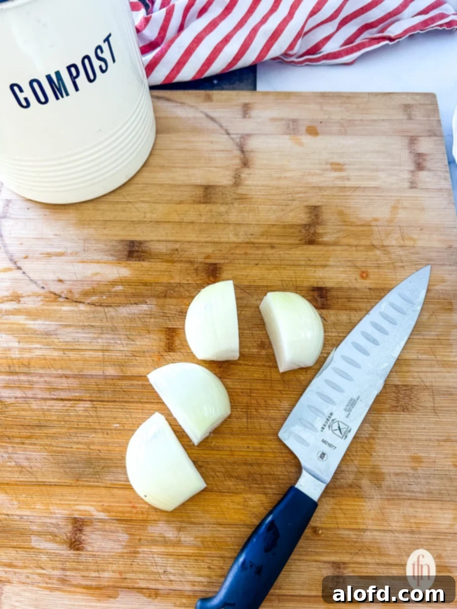 Finely chopped white onion on a cutting board, ready for the food processor, next to a chef's knife.
