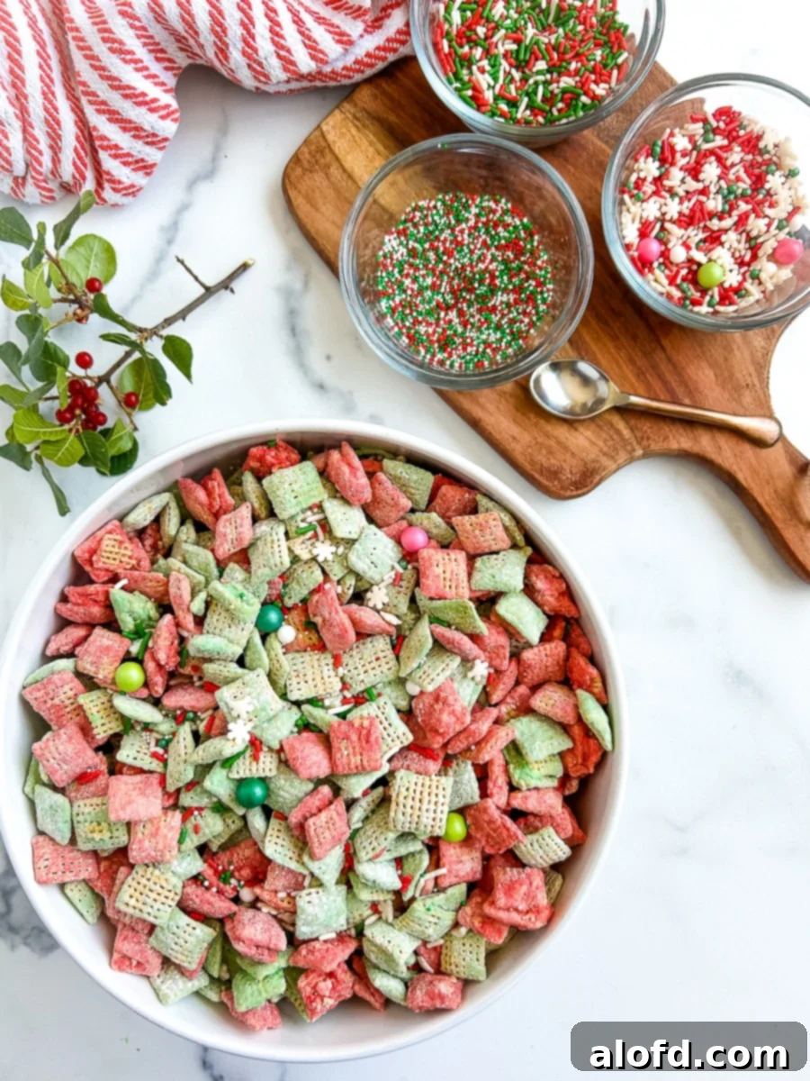 Festive Muddy Buddies 2 Large bowl of sweet and colorful cereal next to a smaller glass bowls of sprinkles on a white surface.