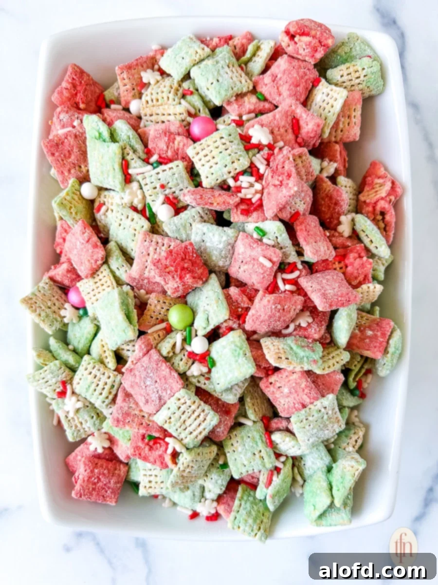 Festive Muddy Buddies 4 Sweet snack mix with red and green coated cereal in a white serving bowl.
