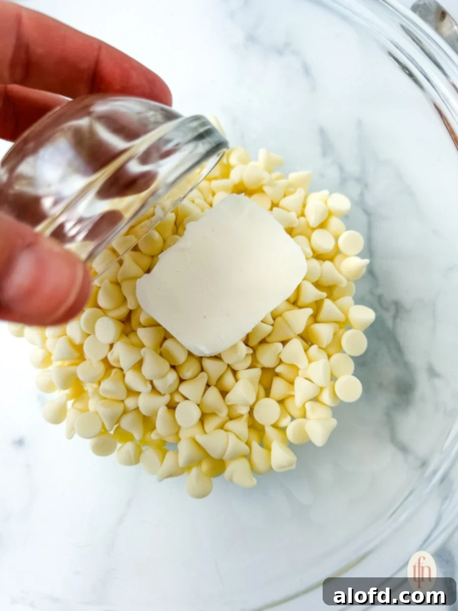 Festive Muddy Buddies 6 Adding Crisco shortening to white chocolate chips in a large glass bowl.