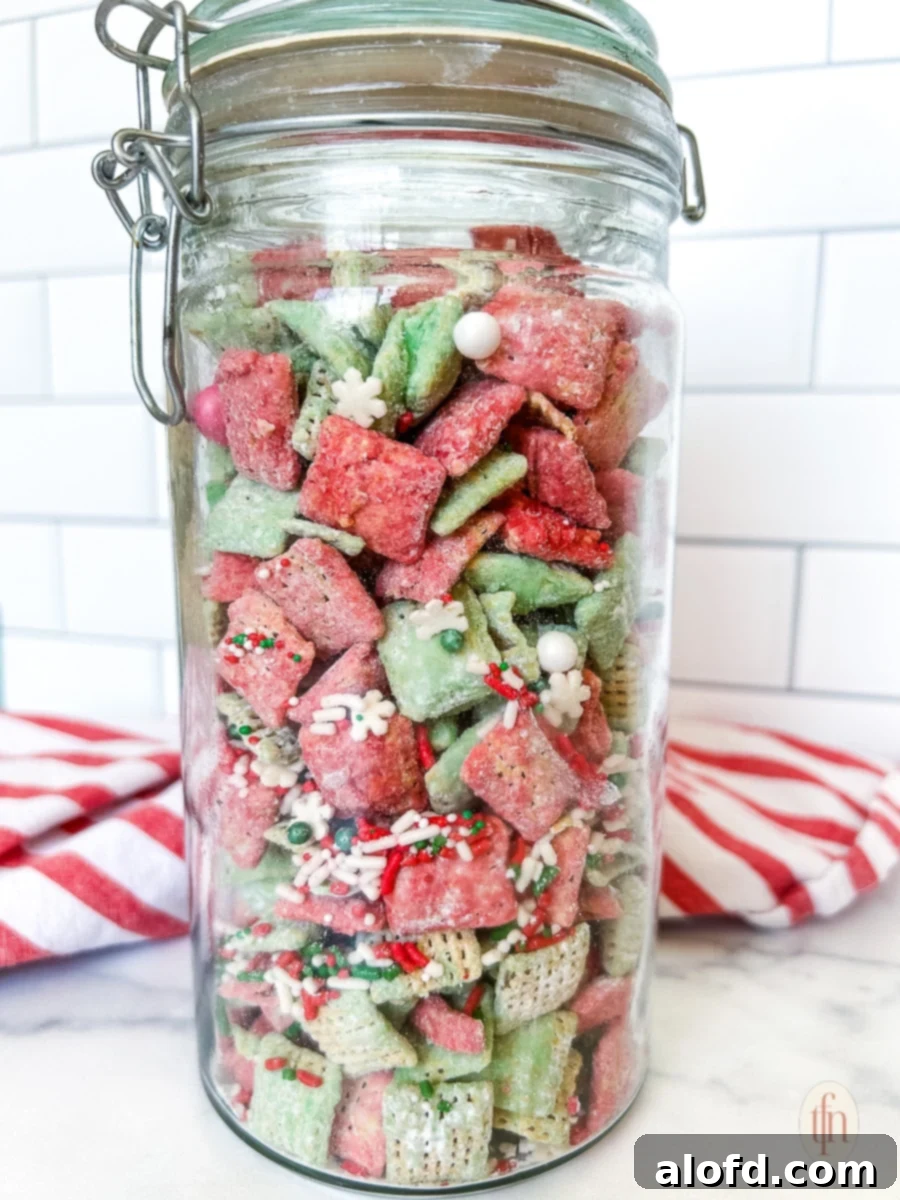 Festive Muddy Buddies 10 Christmas puppy chow in a tall glass canister on a marble countertop.