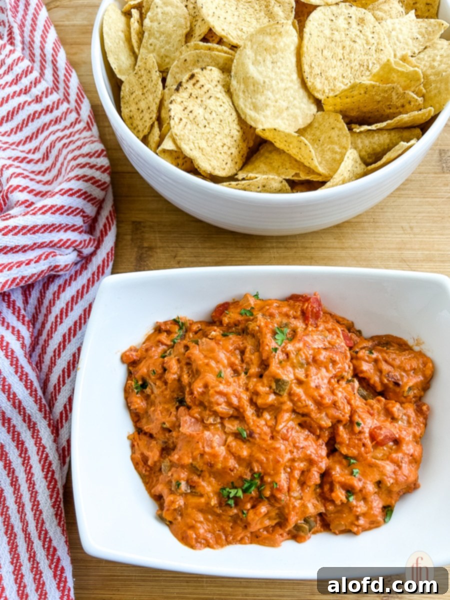 A bowl of rich, smoky queso dip with chorizo, alongside a bowl of crispy tortilla chips.