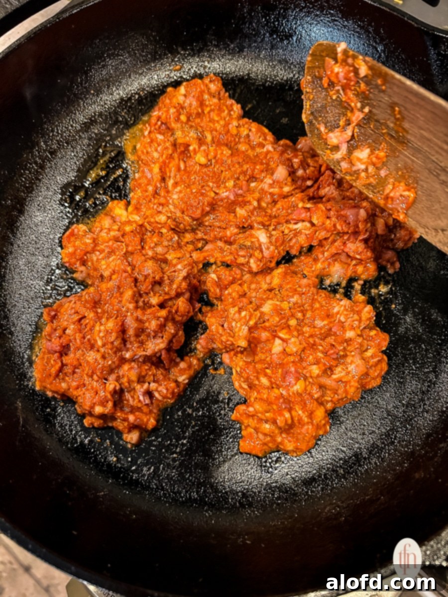 Browning ground pork chorizo in a cast iron skillet on a stovetop.
