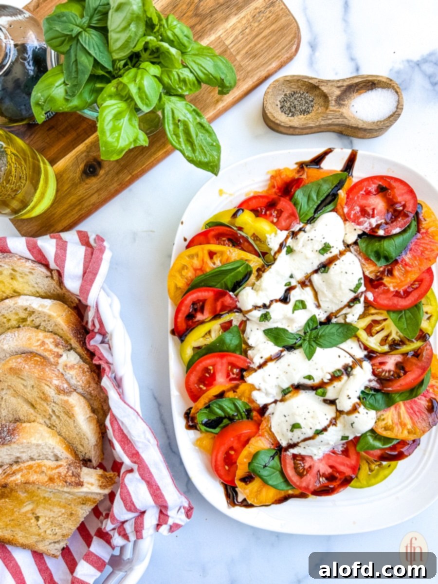 Fresh tomato slices on a white platter with creamy burrata cheese and fresh basil.