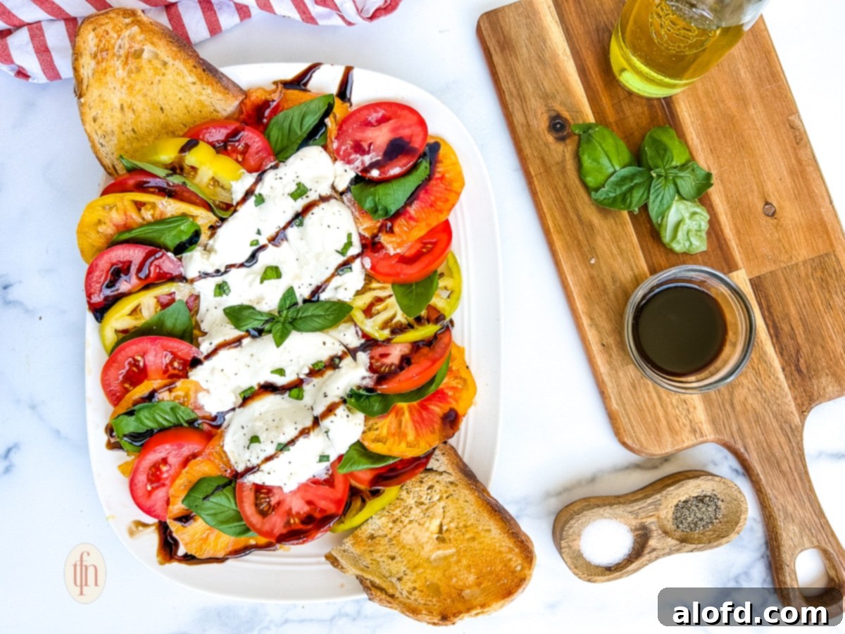 Beautifully presented caprese burrata salad with slices of sourdough garlic bread.