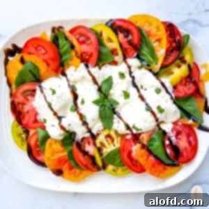 Platter of heirloom tomato salad with creamy white cheese and balsamic drizzle on top.