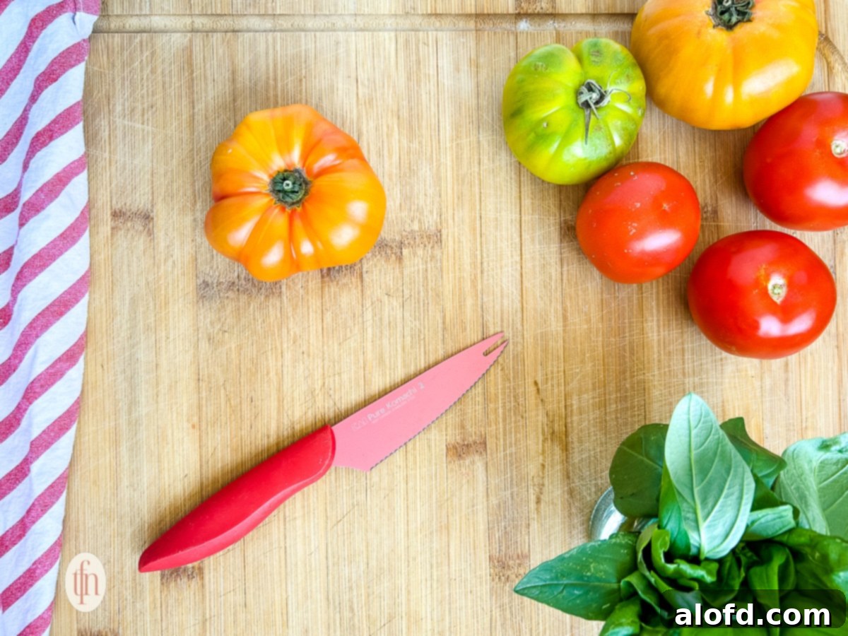 Ingredients for a burrata caprese salad on a cutting board.