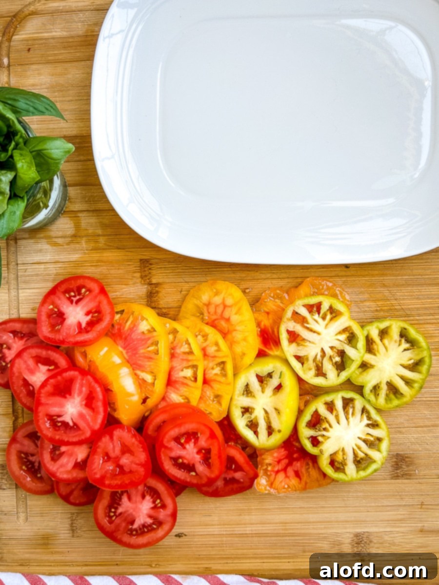 Empty white serving platter next to slices of heirloom tomatoes.