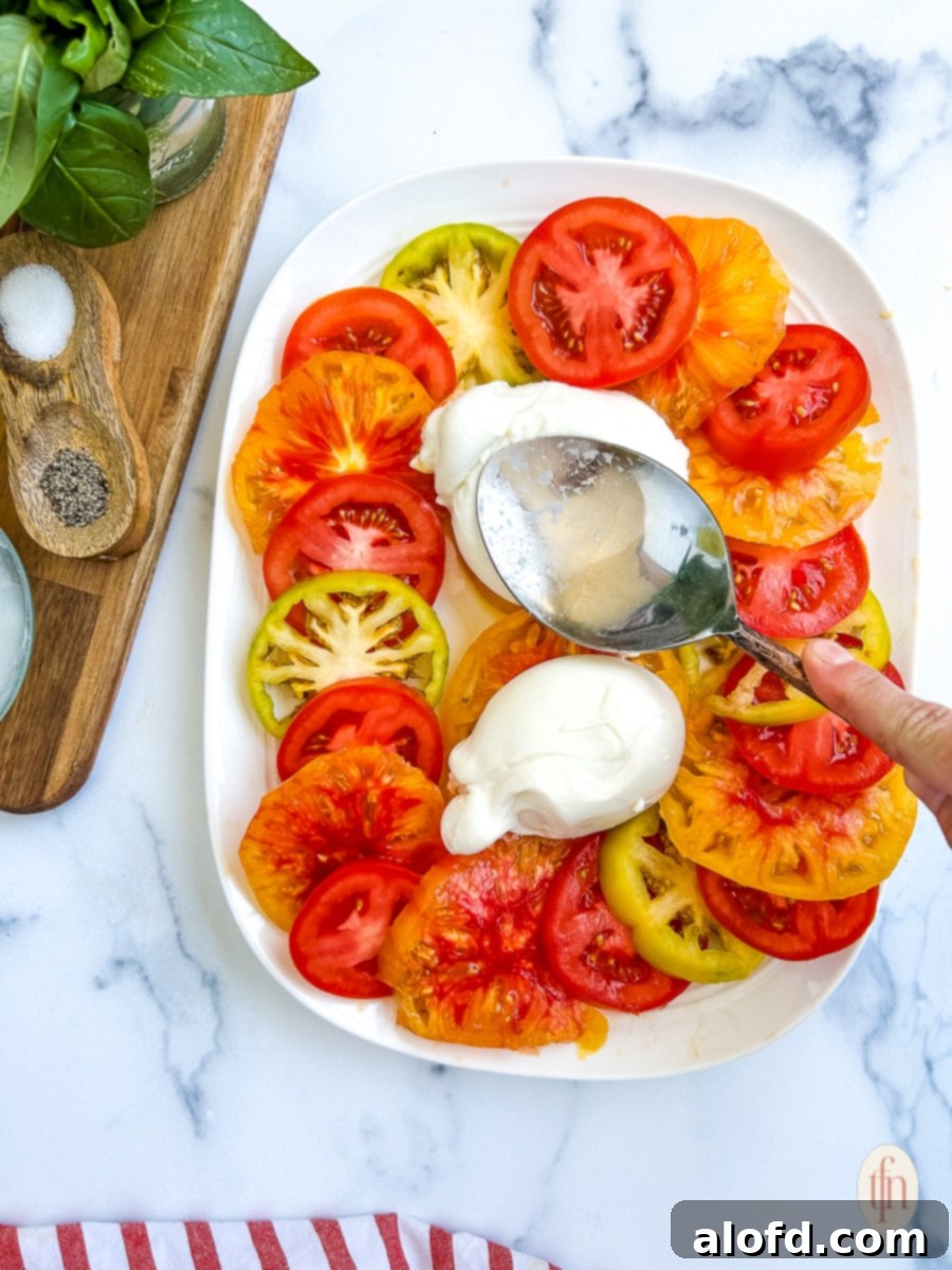 Spreading cheese onto a burrata salad.