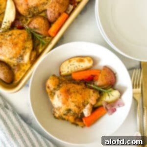 Sheet pan chicken thighs plated with roasted vegetables and fresh herbs, ready to be served.