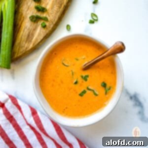 Dynamite Sweet Chili Sauce 10 Copper spoon in a small dish of bang bang sauce with scallion garnish.