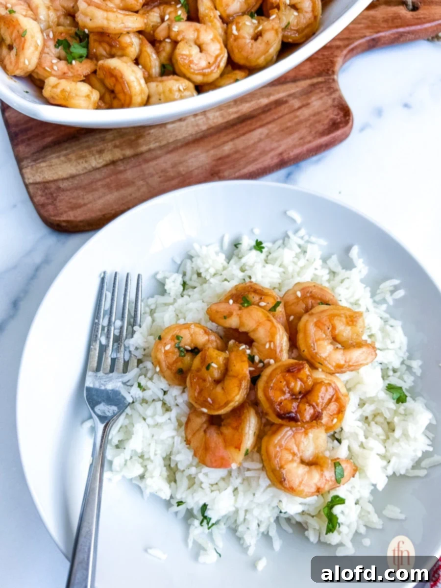A bowl of Blackstone hibachi shrimp served over fluffy white rice, with a fork poised for a delicious bite.