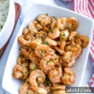 Blackstone hibachi shrimp on a white platter next to a bowl of white rice, ready to be enjoyed.