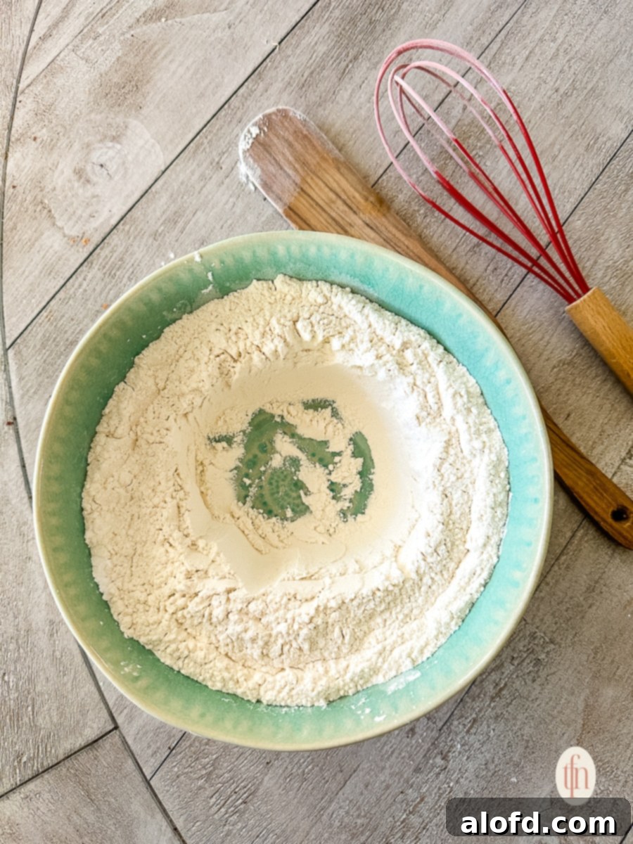 Buttermilk Biscuits with a Tangy Twist 7 Whisked dry ingredients in a blue bowl next to a whisk on a table.