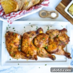 Juicy Smoked Chicken Drumsticks 11 Platter of cooked chicken quarters on a white plate sprinkled with parsley flakes.