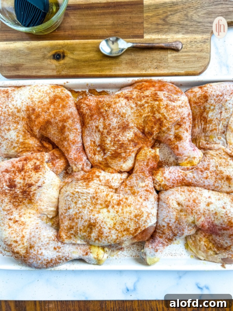 Juicy Smoked Chicken Drumsticks 5 Raw chicken quarters generously sprinkled with paprika arranged on a white platter, ready for smoking.