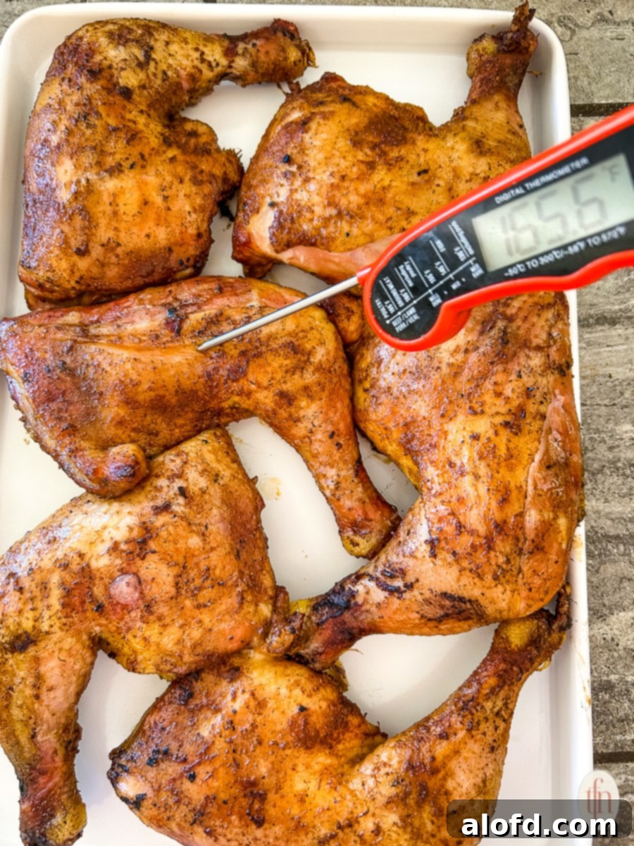 Juicy Smoked Chicken Drumsticks 7 A chicken quarter on a white platter being tested for internal temperature with a digital thermometer, ensuring it's perfectly cooked.