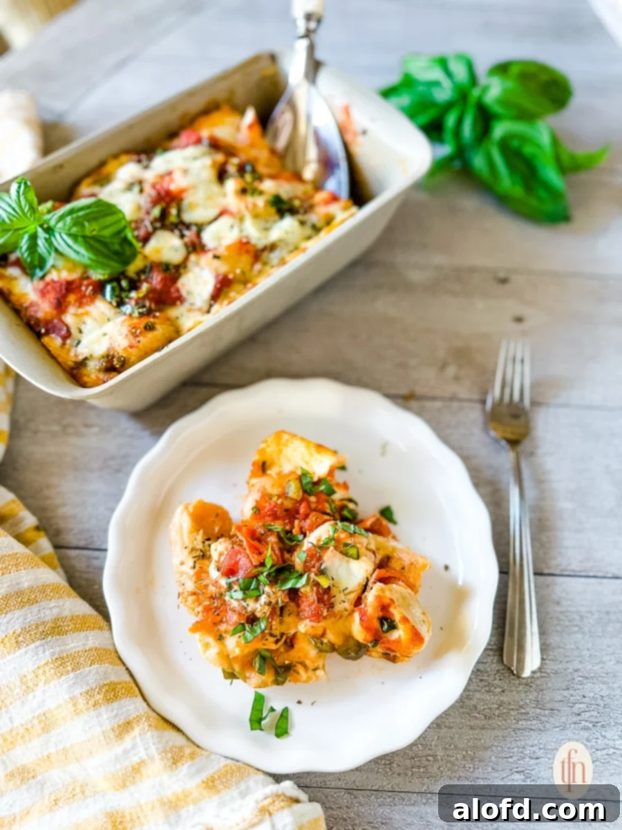 Shortcut Monkey Bread with Frozen Dough 2 Golden-brown pan of baked pull-apart pizza bread casserole, with a plated serving garnished with fresh basil in front of it.