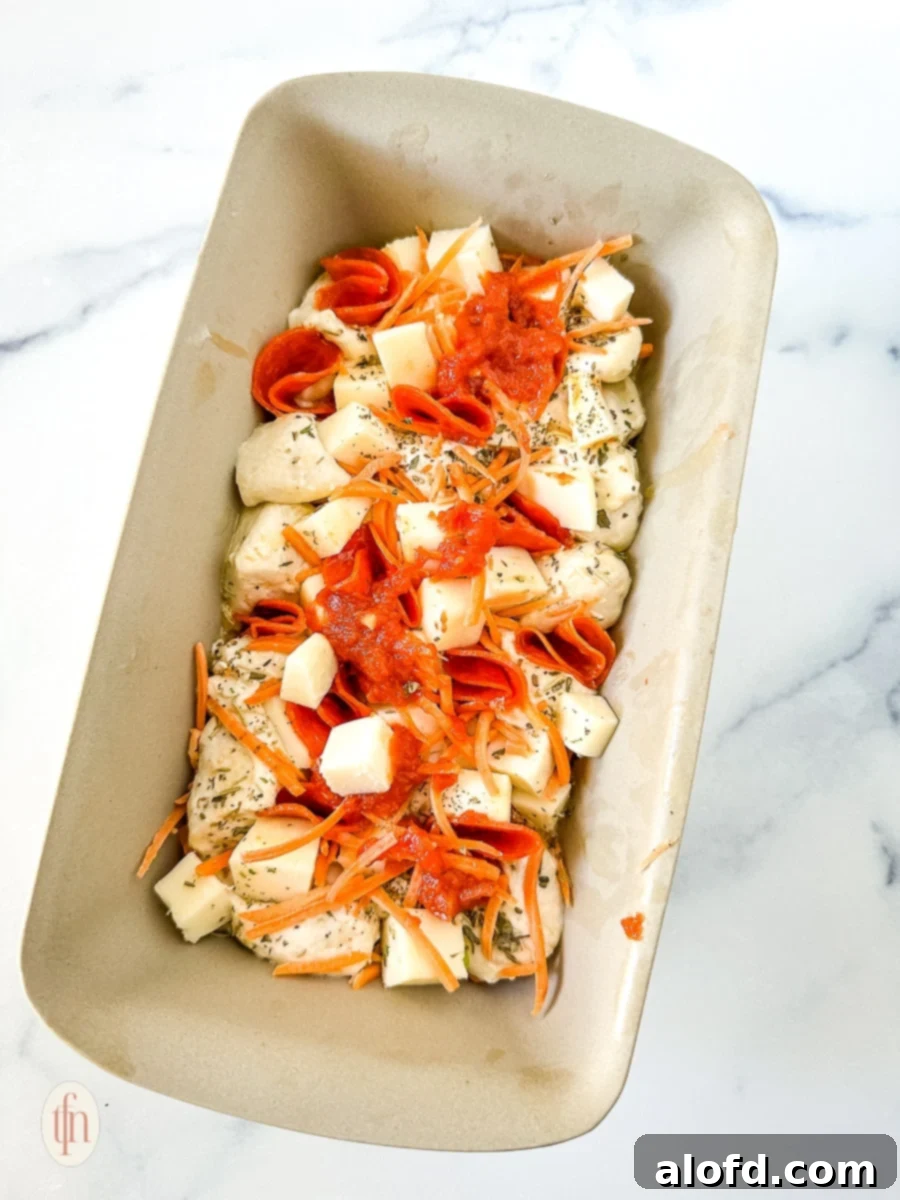Shortcut Monkey Bread with Frozen Dough 10 Assembling layers of dough, sauce, cheese, and pepperoni in a baking pan for pull-apart pizza bread.
