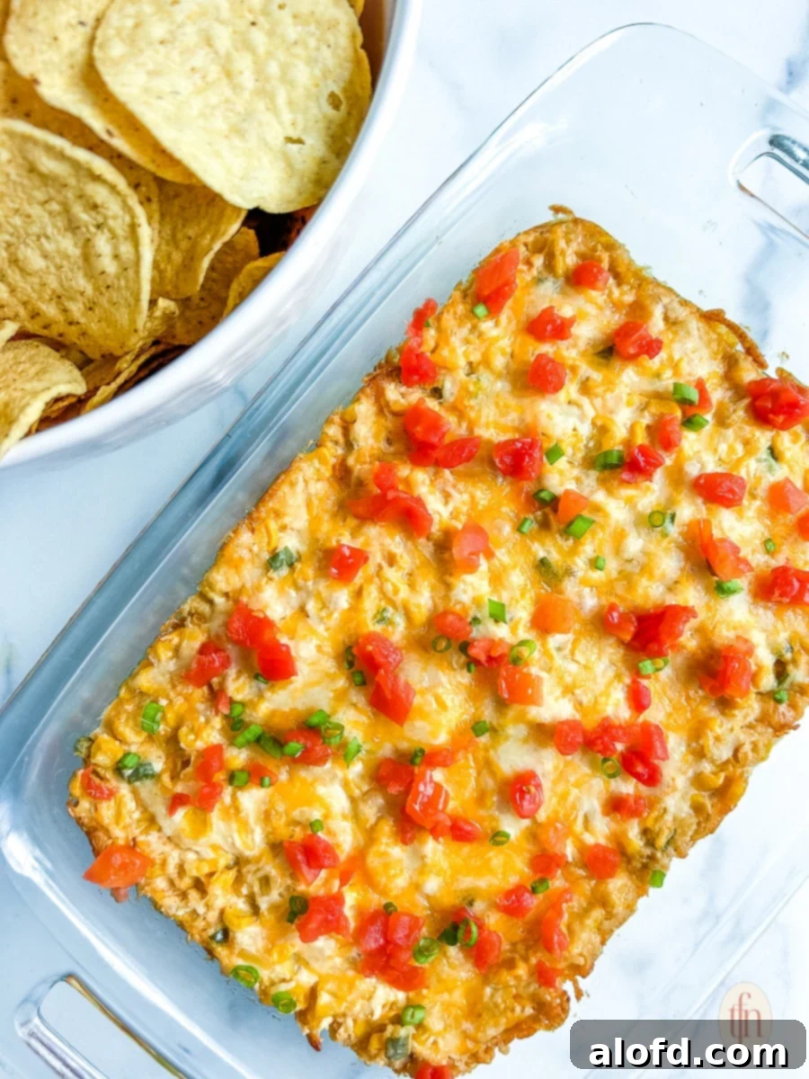 Serving dish with golden-brown cream cheese corn dip, ready to be enjoyed on a white background.
