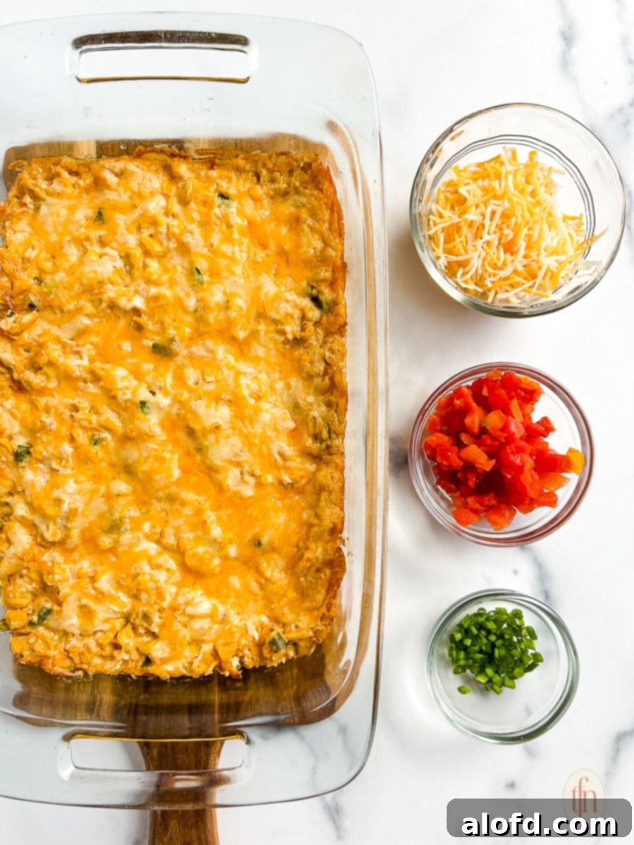 Warm, baked corn dip served in a glass dish, with small bowls of fresh toppings like green onions and cilantro on the side.