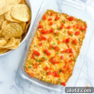 Serving dish with cream cheese corn dip on a white background, garnished with fresh herbs.
