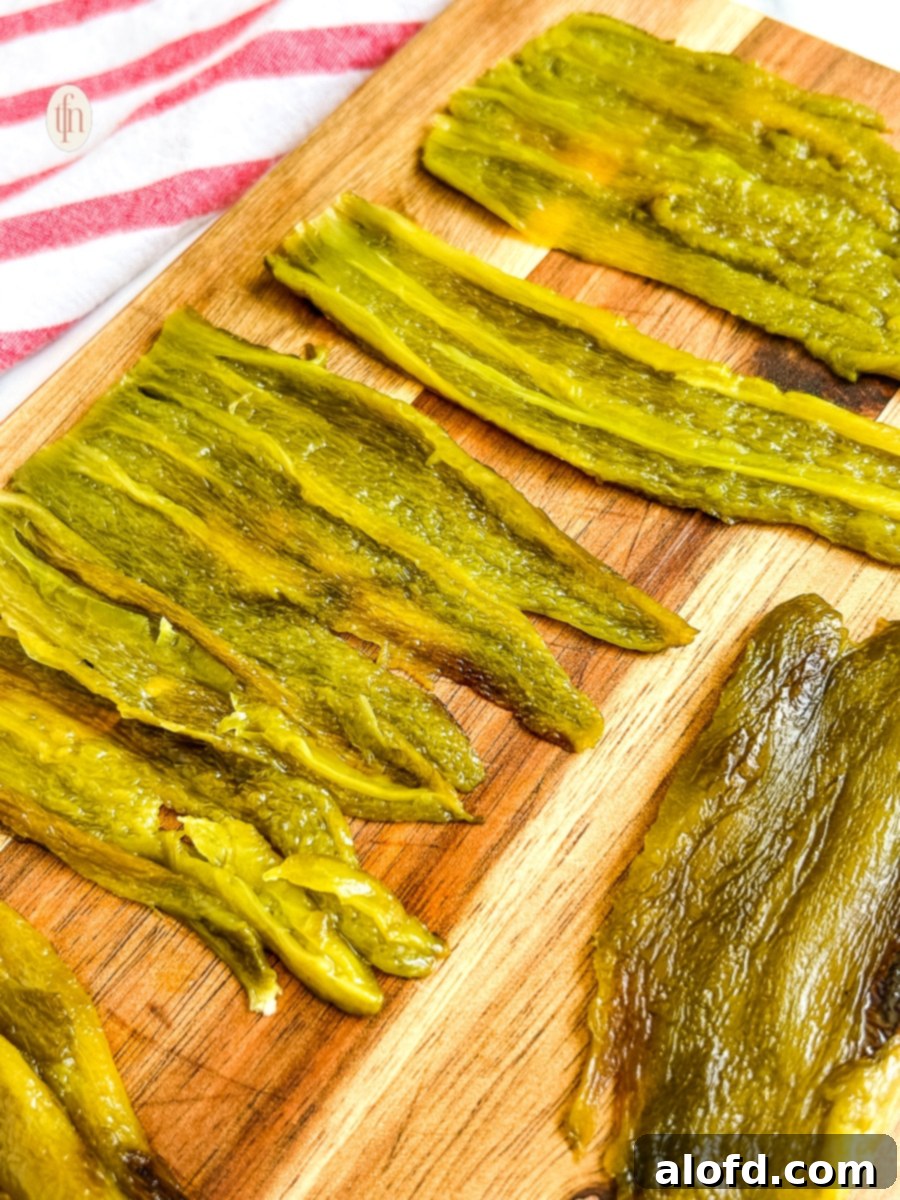 Long strips of green chilies on a cutting board.
