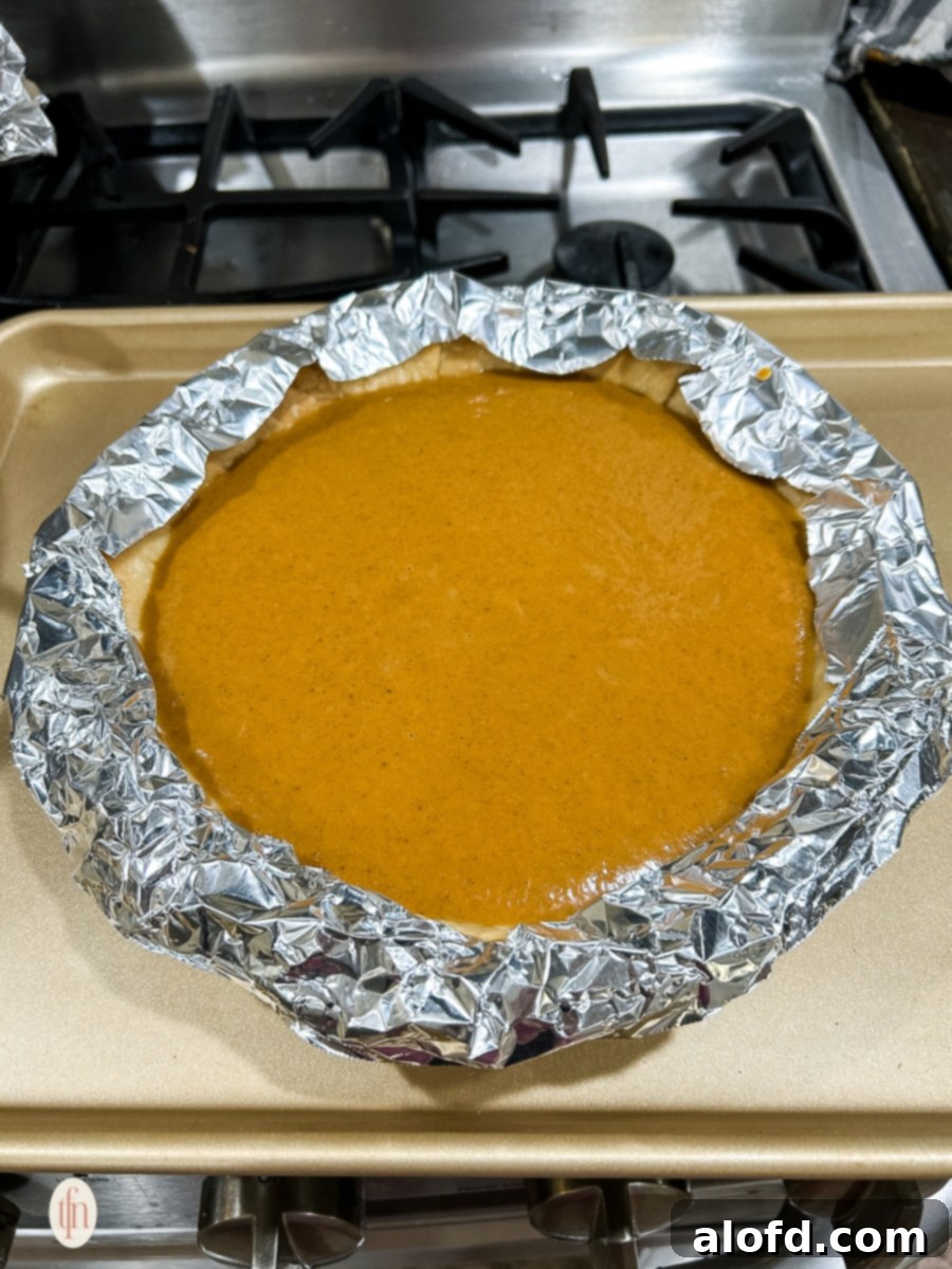 Velvety Pumpkin Custard Pie 8 Pie ready to be baked with foil on the crust.