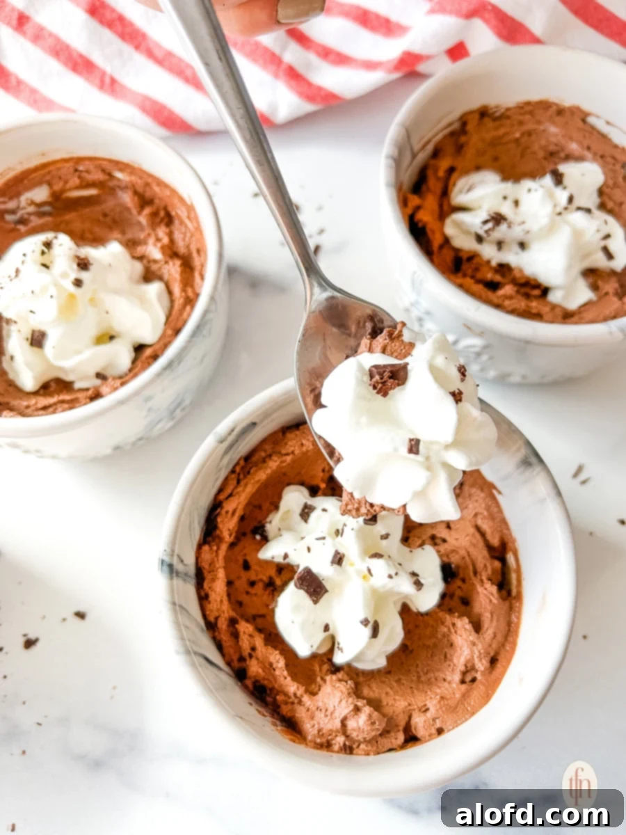Simple Decadent Chocolate Mousse 2 Spoon lifting whipped cream and mousse from a small bowl.